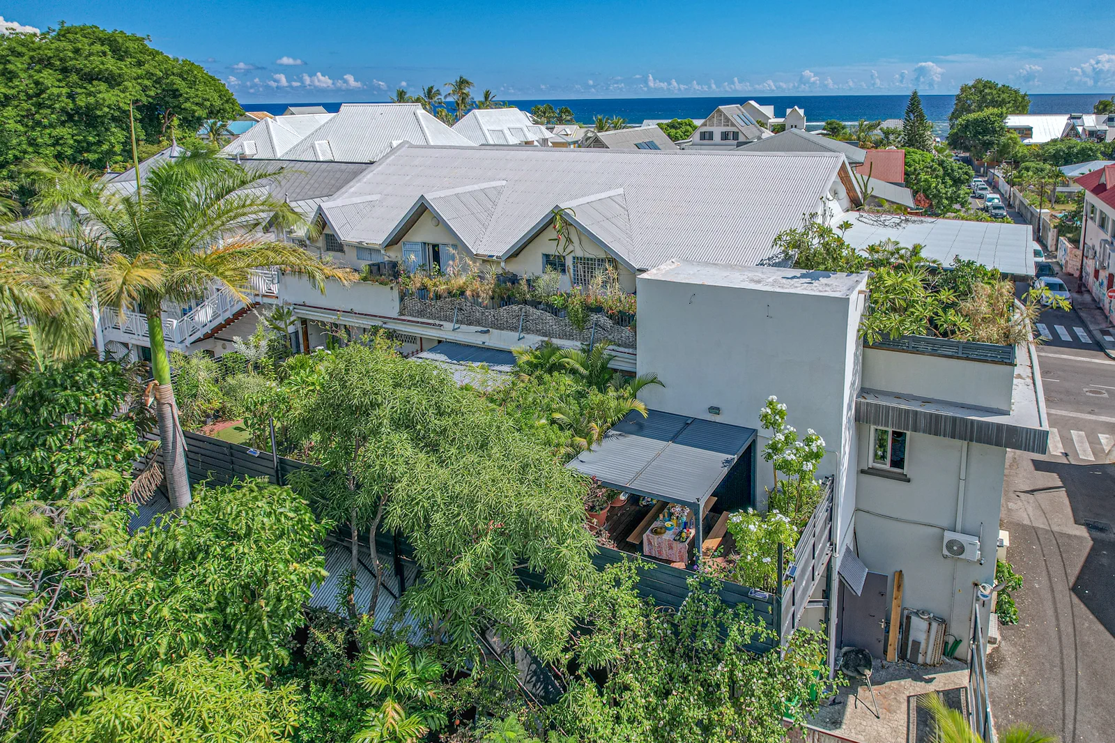 Terrasse en bois avec table, chaises et palmiers chez LELALEU à Saint-Leu